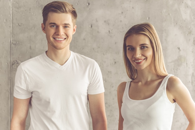 Beau jeune couple regarde la caméra et souriant.