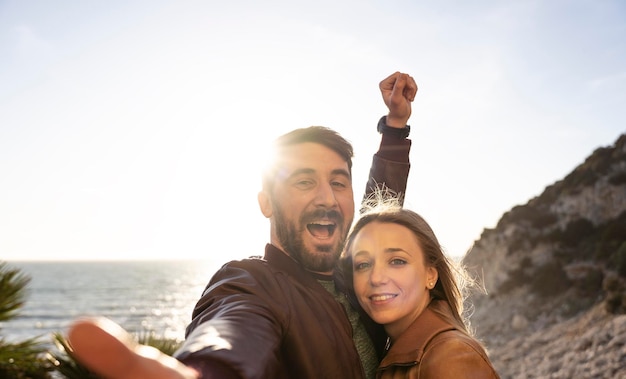 Beau jeune couple s'amusant à prendre un selfie portrait contre un beau panorama au coucher du soleil Petit ami et petite amie amoureux souriant ensemble à la caméra Concept de personnes et de style de vie