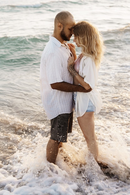 Beau jeune couple s'embrassant sur la plage au bord de l'eau