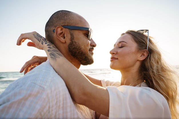 Beau jeune couple s'embrassant sur la plage au bord de l'eau