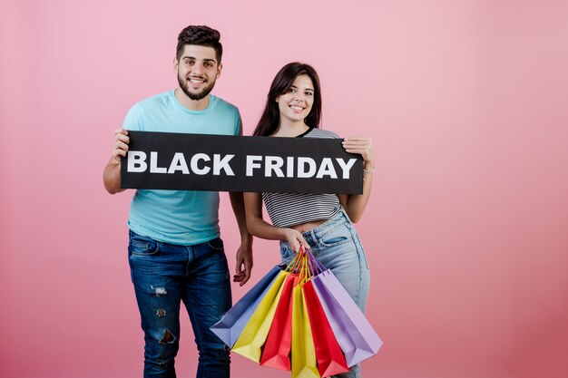 Beau jeune couple et sa petite amie avec signe de vendredi noir et sacs colorés