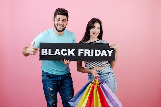 Beau jeune couple et sa petite amie avec signe de vendredi noir et sacs colorés