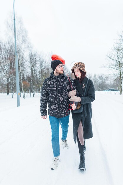 Un beau jeune couple se promène ensemble un jour d'hiver dans un parc enneigé