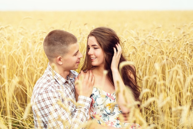 Beau jeune couple se repose sur un champ de blé