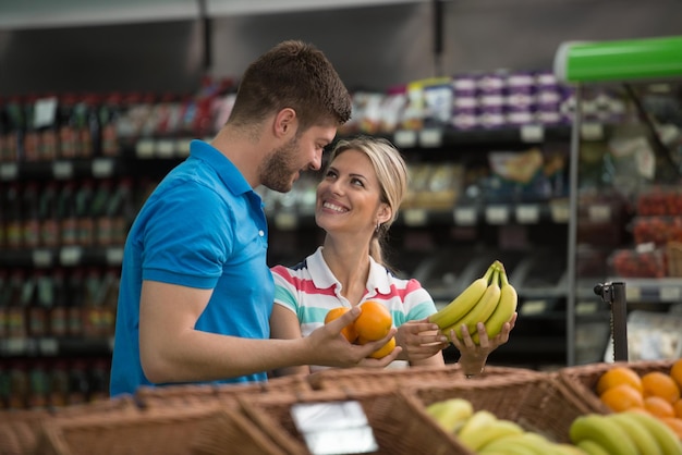 Beau jeune couple Shopping pour les fruits et légumes dans le département des produits d'un supermarché d'épicerie à faible profondeur de champ