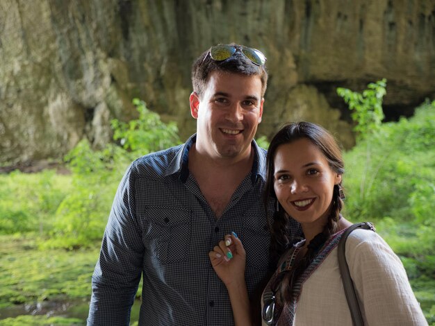 Beau jeune couple souriant à la caméra dans une grotte de montagne. Couple explorant la nature.