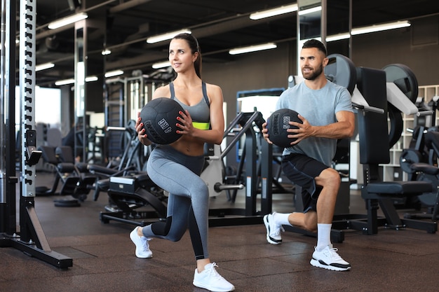 Beau Jeune Couple Sportif Travaille Avec Médecine-ball Dans La Salle De Gym.