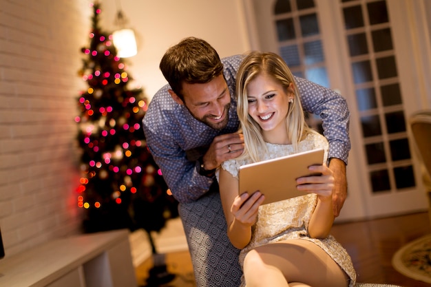 Beau jeune couple avec tablette au réveillon