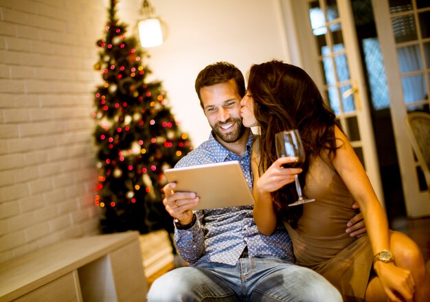 Beau jeune couple avec tablette au réveillon