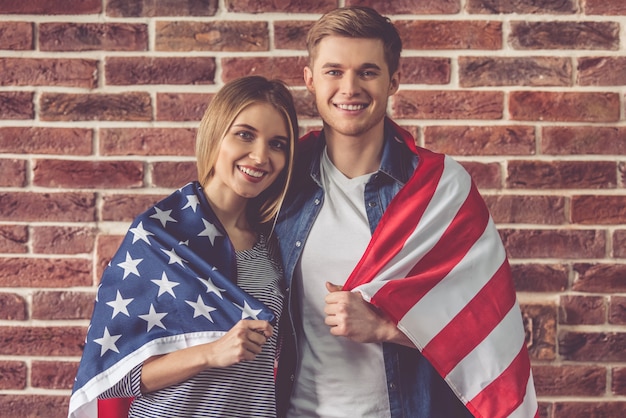 Beau jeune couple tient le drapeau américain.
