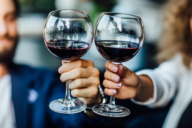 Beau jeune couple avec des verres de vin rouge dans un restaurant de luxe