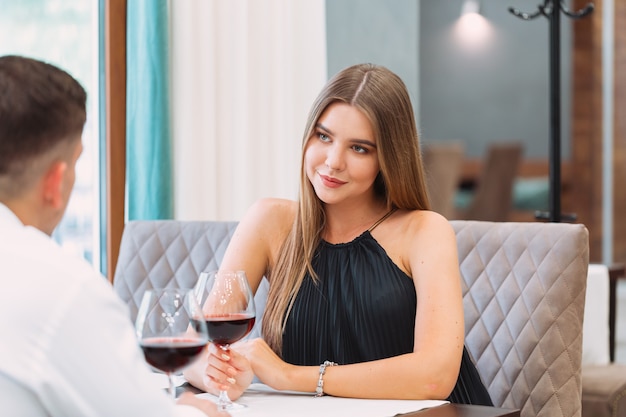 Beau jeune couple avec des verres de vin rouge dans un restaurant de luxe