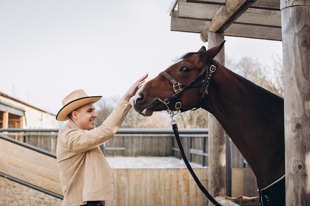 Beau jeune cow-boy dans un ranch avec un cheval