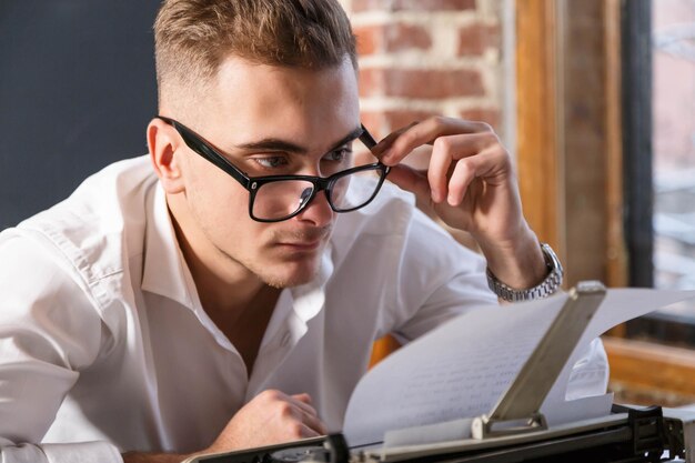 Beau jeune écrivain portant des lunettes et