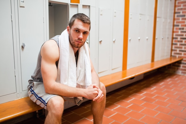 Beau jeune étudiant sportif assis sur un banc