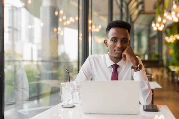 Beau jeune homme d'affaires africain dans un café-restaurant