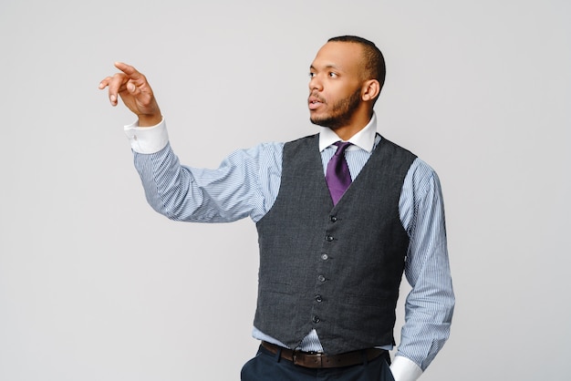 Beau jeune homme d'affaires afro-américain pointant son doigt vers l'écran virtuel.