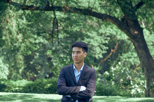 Un beau jeune homme d'affaires asiatique debout dans le parc