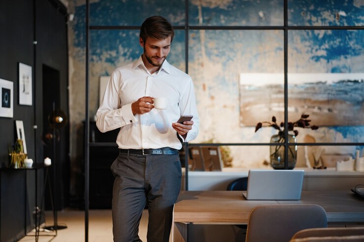 Photo beau jeune homme d'affaires barbu au bureau à l'aide de téléphone mobile à l'intérieur