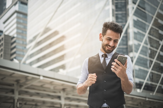 Un beau jeune homme d&#39;affaires barbu utilisant son smartphone