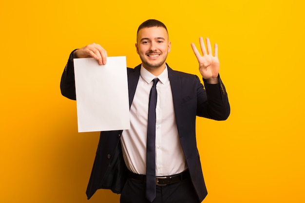 Beau jeune homme d'affaires contre un fond plat tenant un morceau de papier vide