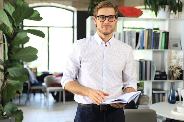 Beau jeune homme d'affaires debout dans un bureau moderne