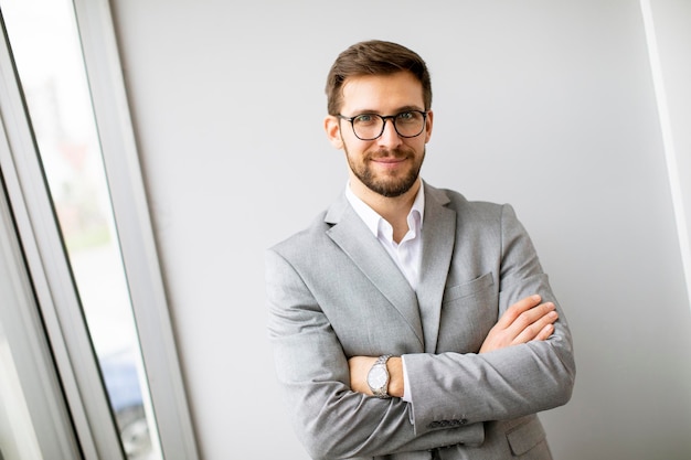 Beau jeune homme d'affaires moderne debout près du mur du bureau