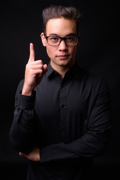 Beau jeune homme d'affaires multiethnique contre le mur noir