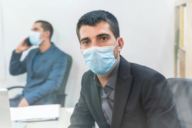 Beau jeune homme d'affaires portant un masque de protection sur fond blanc