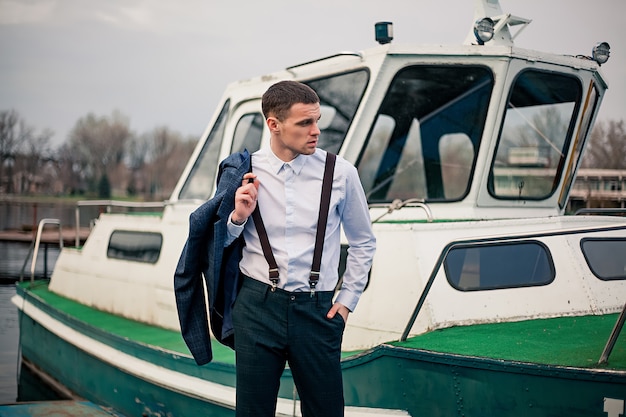 Beau jeune homme d'affaires se dresse sur le quai à la station de bateau