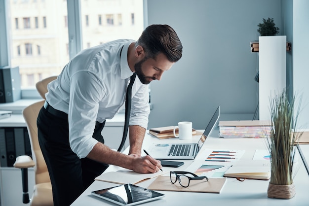 Beau jeune homme d'affaires travaillant sur le bureau