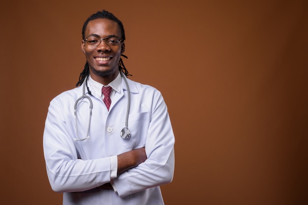 Beau jeune homme africain médecin sur fond marron