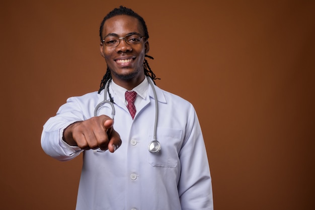 Beau jeune homme africain médecin sur fond marron