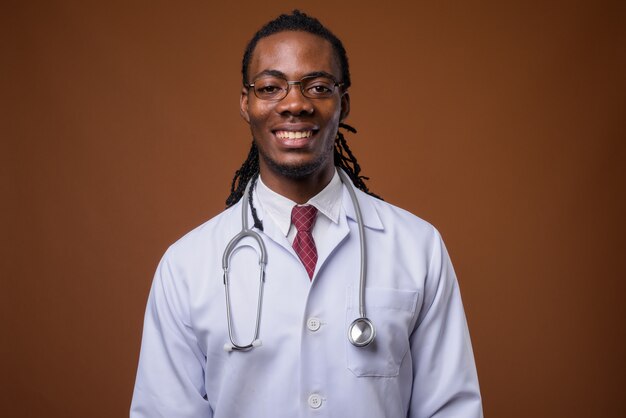 Beau jeune homme africain médecin sur fond marron