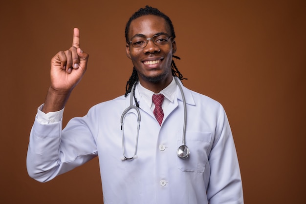 Beau jeune homme africain médecin sur fond marron