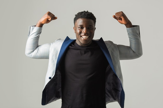 Beau jeune homme africain en veste avec les mains levées