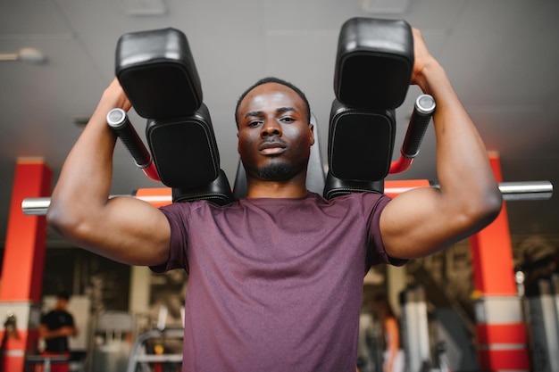 Beau jeune homme afro-américain travaillant à la salle de gym