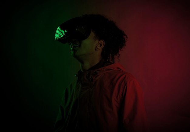 Beau jeune homme afro souriant avec casque de réalité virtuelle et éclairage coloré. Lunettes de haute technologie pour la réalité virtuelle.