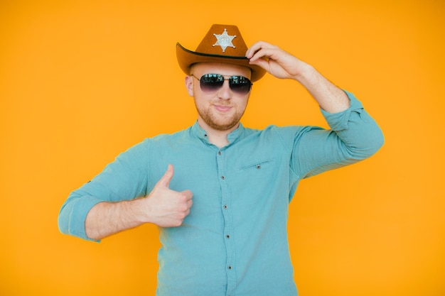 Beau jeune homme ajustant son chapeau de cowboy