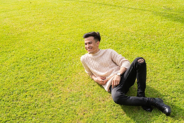 Beau jeune homme allongé sur l'herbe pendant l'été au parc