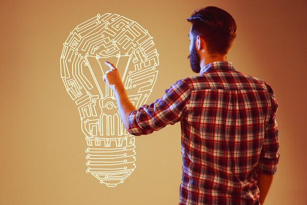 Beau jeune homme avec ampoule idée sur fond de lampe abstraite. Concept nouvelle idée