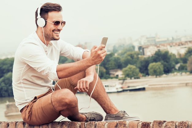 Beau jeune homme appréciant la musique un jour d'été