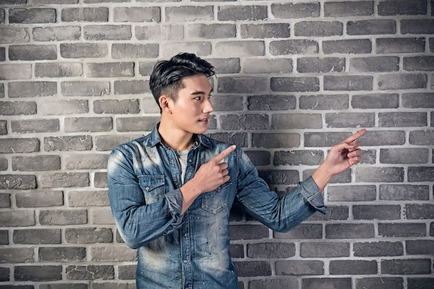 Beau jeune homme asiatique contre le mur de briques grises