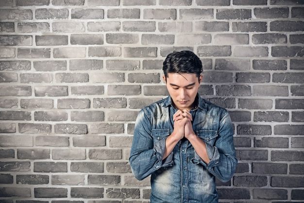 Beau jeune homme asiatique contre le mur de briques grises