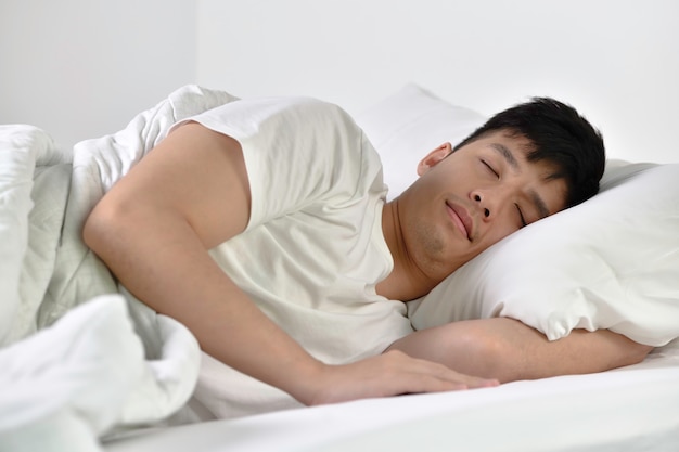 Beau jeune homme asiatique dormant dans son lit