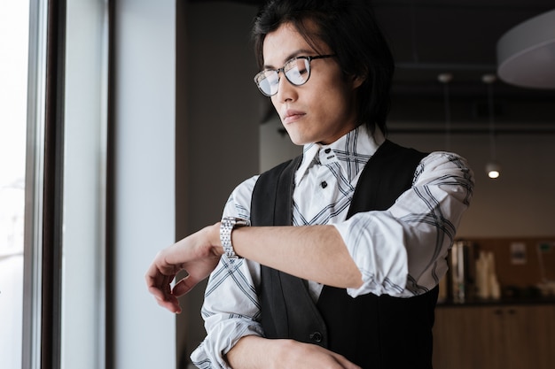 Beau jeune homme asiatique regardant la montre.