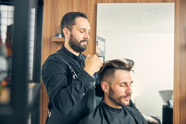 Beau jeune homme assis les yeux fermés en attendant sa nouvelle coiffure