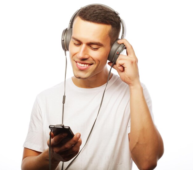 Beau jeune homme au casque en se tenant debout sur fond blanc