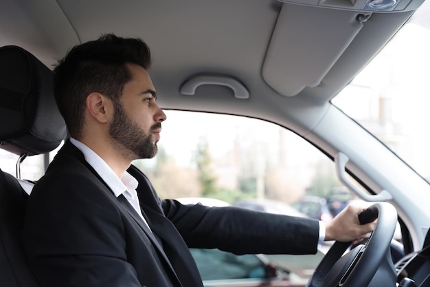 Beau jeune homme au volant de sa voiture moderne