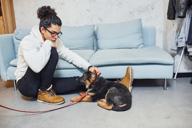 Beau jeune homme aux cheveux noirs bouclés à l'intérieur avec un chien mignon.